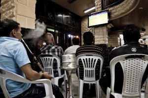 People smoke hookah and watching a football match inside a bar of Tunis on October 16, 2012.