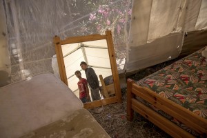 Pakistani migrants are reflected in a mirror inside a tent near an abandoned hotel where many migrants sleep in Kos island, Greece on June 8, 2015. Many migrants are continuing to arrive on the Greek Island of Kos from Turkey. The Island has recently seen a drop in tourist numbers which has been attributed to negative reports on the migrant crisis that is continuing to grip the area. Around 30,000 migrants have entered Greece so far in 2015, with the country calling for more help from its European Union counterparts.