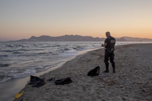 A policeman controls a beach after the arrival from the sea of Pakistani migrants in Kos island, Greece on June 15, 2015.