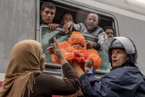 Police guard helps a baby to get the train heading for Zagreb as migrants desperately try to continue their journey in the north of Europe despite moves by Slovenia and Hungary to hold them back in Tovarnik, Croatia on September 20, 2015.