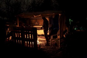 January 29, 2016 – Grande-Synthe, France: A migrant gets warm near a fire inside the refugee  camp of Grande-Synthe near Dunkirk, northern France, known as “The Jungle 2″. Around 3,000 refugees and migrants of Kurdish descent from Iraq and Syria live in the camp.