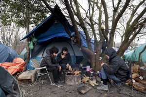 January 29, 2016 – Grande-Synthe, France: Migrants get warm near a fire inside the refugee  camp of Grande-Synthe near Dunkirk, northern France, known as “The Jungle 2″. Around 3,000 refugees and migrants of Kurdish descent from Iraq and Syria live in the camp.