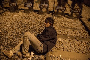 A man sits in front of a line of Greek police in riot gear at the Idomeni camp in Greece on March 21, 2016. The refugees have been demanding the reopening of the border with Macedonia, in the hopes of making their way to northern Europe.