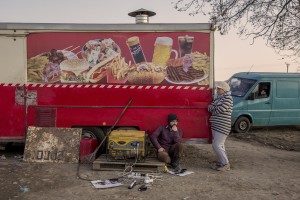 Refugees rest near a catering van at the Idomeni camp near the border of Greece and Macedonia, where they have been stranded in the rain, mud and cold in Idomeni, Greece on March 19, 2016.