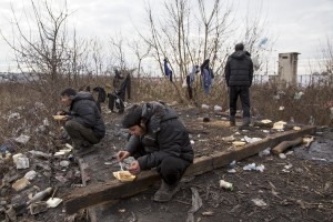 Migrants sit eating their lunch outside an abandoned warehouse where they took refuge in Belgrade, Serbia on February 3, 2017. Hundreds of migrants have been sleeping in freezing conditions in central Belgrade looking for ways to cross the heavily guarded EU borders.