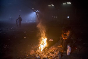 A migrant sits around a fire to warm himself from the cold in an abandoned warehouse in Belgrade, Serbia on February 3, 2017. Hundreds of migrants have been sleeping in freezing conditions in downtown Belgrade looking for ways to cross the heavily guarded EU borders.