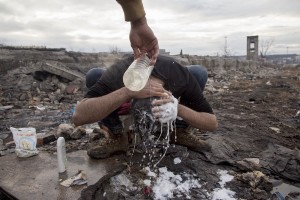 A refugee washes his hair outside an abandoned warehouse where they took refuge in Belgrade, Serbia on February 3, 2017. Hundreds of migrants have been sleeping in freezing conditions in central Belgrade looking for ways to cross the heavily guarded EU borders.