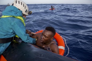 A member of German NGO Sea-Watch (L) helps a migrant to board a boat after he was recovered in the Mediterranean Sea on November 6, 2017. During a shipwreck, five people died, including a newborn child. According to the German NGO Sea-Watch, which has saved 58 migrants, the violent behavior of the Libyan coast guard caused the death of five persons. Alessio Paduano