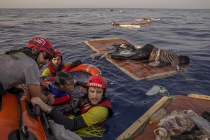 Members of the Spanish NGO Proactiva Open Arms rescue Josepha, an African migrant from Cameroon, while the body of a woman lies on a piece of drift wood about 85 miles off the Libyan coast in the Mediterranean sea on July 17, 2018.