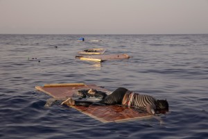 The body of a woman lies on a piece of drift wood as members of the Spanish NGO Proactiva Open Arms rescue her floating body about 85 miles off the Libyan coast in the Mediterranean sea on July 17, 2018.