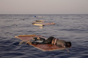 The body of a woman lies on a piece of drift wood as members of the Spanish NGO Proactiva Open Arms rescue her floating body about 85 miles off the Libyan coast in the Mediterranean sea on July 17, 2018.