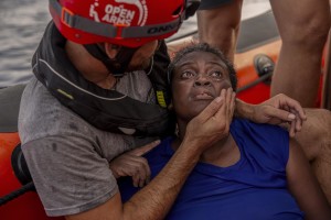 A crew member of the Spanish NGO Proactiva Open Arms rescue boat embraces Josepha, an African migrant from Cameroon, in the Mediterranean sea on July 17, 2018.
