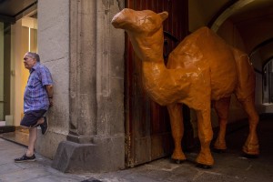 A man is portrayed near the statue of a camel in the Raval district in Barcelona, Spain on July 12, 2018. The Raval is one of the most multicultural and colorful neighborhoods in the city and it hosts numerous artists and galleries.