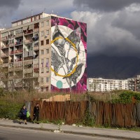 People walk near the mural entitled “‘O sciore cchiù felice” (the happiest flower) realized by the Italian street artist “Fabio Petani” inside the so called “Park of murals” in Ponticelli, near Naples, Italy on April 8, 2019. An artistic redevelopment and social regeneration program promoted by INWARD (observatory on urban creativity) has been starting since 2015.