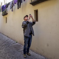 A tourist takes a picture during the street art tour organized by the cultural association “400 ml” in Naples, Italy on March 24, 2019. Napoli Paint Stories street art and graffiti tour is a touristic walk in the neapolitan historical center through murales,stencils,slogans,posters and graffiti to discover urban art.