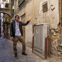 A tour guide shows a graffiti of the florentine street artist “Exit Enter k” in the alleys of the Neapolitan historical center, during a street art tour organized by the cultural association “400 ml” in Naples, Italy on March 24, 2019. Napoli Paint Stories street art and graffiti tour is a touristic walk in the neapolitan historical center through murales, stencils, slogans, posters and graffiti to discover urban art.