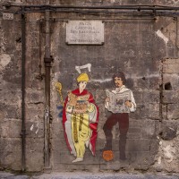 A stencil depicting Saint Januarius and the painter Caravaggio realized by the Neapolitan artist “Roxy in the box” is seen on a wall of the historical center of Naples, in Italy on March 19, 2019.