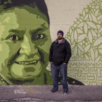 A portrait of the street artist Gianluca “Raro” near a mural depicting Rigoberta Menciù, a Guatemalan pacifist who received the Nobel Peace Prize in 1992, in Scampia district, Naples, Italy on March 9, 2019. The mural is located near the ”garden of non-violence and the five continents” and is part of a project realized by “Raro” and Fabio della Ratta “biodpi”,  with the collaboration of three boys from Gambia.