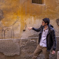 A tour guide shows a graffiti of the street artist “Exit Enter k” in the alleys of the Neapolitan historical center, during a street art tour organized by the cultural association “400 ml” in Naples, Italy on March 24, 2019. Napoli Paint Stories streetart and graffiti tour is a touristic walk in the neapolitan historical center through murales, stencils, slogans, posters and graffiti to discover urban art.