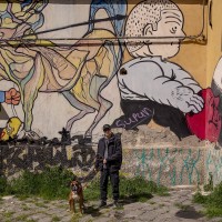 A boy and his dog are seen near some murals outside the social center “Ex-OPG occupato- Je so’ pazzo” in Naples, Italy on March 24, 2019.