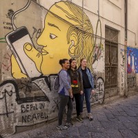 Tourists during a street art tour organized by the cultural association “400 ml” in Naples, Italy on March 24, 2019. Napoli Paint Stories streetart and graffiti tour is a touristic walk in the neapolitan historical center through murales,stencils,slogans,posters and graffiti to discover urban art.