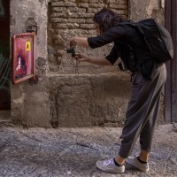 A woman takes a picture during the street art tour organized by the cultural association “400 ml” in Naples, Italy on March 24, 2019. Napoli Paint Stories street art and graffiti tour is a touristic walk in the neapolitan historical center through murales, stencils, slogans, posters and graffiti to discover urban art.