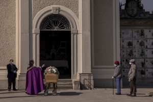 Father Mario Carminati bless the coffin of a coronavirus victim inside the cemetery of Seriate, province of Bergamo, Northern Italy on April 15, 2020.