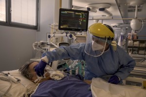 A nurse takes care of a patient who lie in bed inside the coronavirus intensive care unit of the “Papa Giovanni XXIII” hospital in Bergamo, Northern Italy on April 17, 2020.