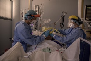 Nurses take care of a patient who lie in bed inside the coronavirus intensive care unit of the “Papa Giovanni XXIII” hospital in Bergamo, Northern Italy on April 17, 2020.