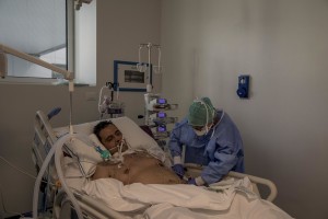 A nurse takes care of a patient who lies in bed inside the coronavirus intensive care unit of the “Poliambulanza Foundation” hospital in Brescia, Italy on April 9, 2020. “Poliambulanza Foundation” is a non-profit multispecialist private hospital, affiliated with the National Health Service.