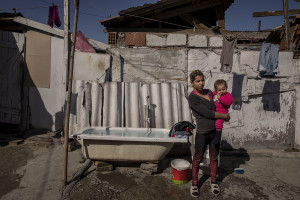 Selma, 18 years old and her daughter are seen outside their house in the area of Shutka in Skopje, North Macedonia on February 29, 2020. During the winter Selma, like many others households, burns coal, scrap wood, textiles or trash in order to keep warm. This obsolete heating system is one of the biggest contributors to air pollution in the country. Although the electricity tariffs in Macedonia are among the lowest in Europe, energy can cost a third or even half of a citizen’s  average monthly salary. This is the reason why many residents burn wood to heat their home, often buying it on the black market where it costs less, but is more toxic to the environment.