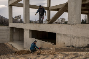 Two men work on the construction of a building nearby “Usje” cement factory in Skopje, North Macedonia on March 3, 2020. According to green activists “Usje” cement factory uses waste as fuel during its production cycle. One of the main causes of air pollution in Skopje are the industries, in general older than in the rest of Europe. As reported on the website republika.mk the company confirmed that it is using petroleum coke and former employees have recently claimed that it was also burning old car tires brought in from Greece. The area around “Usje” cement factory has some of the worst levels of air pollution in Skopje.