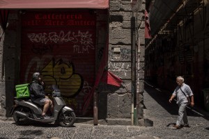 A rider (left) and a man (right) are seen in a street of the historical center of Naples, Italy on June 15, 2020.