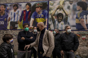 People are seen near pictures of the Argentine soccer legend Diego Armando Maradona in the Spanish Quarter after the announcement of his death, in Naples, Italy on November 26, 2020.