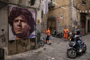 People at work near a mural depicting the Argentine soccer legend Diego Armando Maradona in the Spanish Quarter in Naples, Southern Italy on November 24, 2021. Diego Armando Maradona died on November 25 of last year and next November 25, 2021 will be the anniversary of his death.