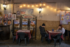 People are seen in a restaurant with pictures depicting the Argentine soccer legend Diego Armando Maradona in the Spanish Quarter in Naples, Southern Italy on November 24, 2021. Diego Armando Maradona died on November 25 of last year and next November 25, 2021 will be the anniversary of his death.