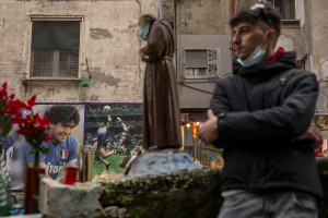 A man is seen near pictures of the Argentine soccer legend Diego Armando Maradona in the Spanish Quarter after the announcement of his death in Naples, Italy, on November 26, 2020.