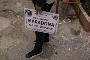 A man holding a funeral poster is seen in the Spanish Quarter after the announcement of the Argentine soccer legend Diego Armando Maradona death in Naples, Italy on November 26, 2020.