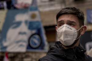A man cries near a picture of the Argentine soccer legend Diego Armando Maradona in the Spanish Quarter after the announcement of his death, in Naples, Italy on November 26, 2020.