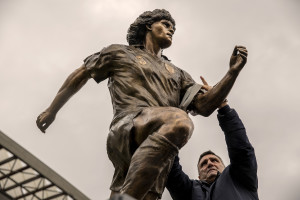 NAPLES, ITALY – NOVEMBER 25: The former Neapolitan football player Bruno Giordano, puts the captain’s armband to the statue depicting the Argentine soccer legend Diego Armando Maradona inside the Maradona stadium in Naples, Southern Italy on November 25, 2021. The statue was made by the Italian sculptor Domenico Sepe.