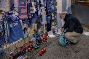 A man is seen near scarves, football shirts and pictures of the Argentine soccer legend Diego Armando Maradona are seen outside San Paolo stadium after the announcement of his death in Naples, Italy on November 27, 2020.