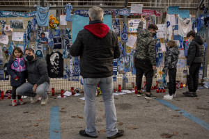 People are seen near carves, football shirts and pictures of the Argentine soccer legend Diego Armando Maradona are seen outside San Paolo stadium after the announcement of his death in Naples, Italy on November 27, 2020.