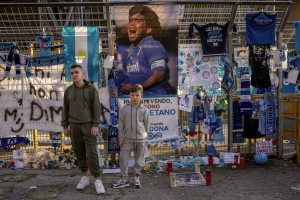 Children are seen near scarves, football shirts and pictures of the Argentine soccer legend Diego Armando Maradona are seen outside San Paolo stadium after the announcement of his death in Naples, Italy on November 27, 2020.