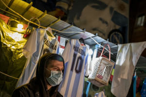 A man is seen near pictures of the Argentine soccer legend Diego Armando Maradona in the Spanish Quarter after the announcement of his death, in Naples, Italy on November 25, 2020.