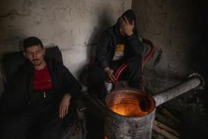 Migrants warm up near a fire inside an abandoned factory in Bihac, Bosnia and Herzegovina on January 22, 2021. Lots of migrants avoid staying inside the Bosnian official refugee camps because of the hard conditions in which they are forced to live and also because the people hosted in the official camps  cannot go out freely.