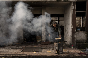 A migrant cooks outisde an abandoned factory in Bihac, Bosnia and Herzegovina on January 23, 2021. Lots of migrants avoid staying inside the Bosnian official refugee camps because of the hard conditions in which they are forced to live and also because the people hosted in the official camps  cannot go out freely.