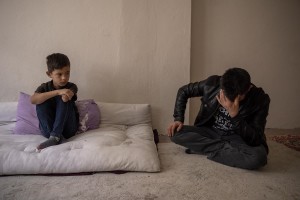 Fazel, 9 years old (left) from Afghanistan watches his father Abdul (right) cry inside the house where they live in Van, Turkey on October 25, 2021. Abdul arrived in Turkey for about two months paying 7200 dollars for the entire family.