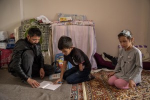 Abdul, 40 years old from Takhar province, Afghanistan helps his son Fazel, 9 years old with homework inside the house where they live in Van, Turkey on October 25, 2021. Abdul arrived in Turkey for about two months paying 7200 dollars for the entire family.