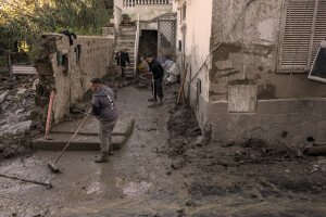 People at work to remove mud from the entrance of a house following a landslide hit the Italian holiday island of Ischia, Southern Italy on November 27, 2022.