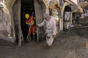 Civil protection operators at work to remove mud from the entrance of a shop following a landslide hit the Italian holiday island of Ischia, Southern Italy on November 27, 2022.